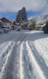 a street covered in snow with tracks in it at Alma de Maitén in San Carlos de Bariloche