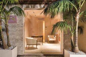 un vestíbulo con palmeras, sillas y una mesa en Taormina Infinity Suites, en Taormina