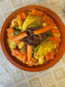 uma tigela de comida com cenouras e legumes numa mesa em Gîte d’étape Chrifi em Anergui