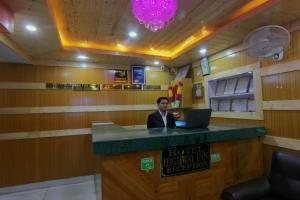 a man sitting at a bar with a laptop at Hotel Highway Inn Manali - Luxury Stay - Excellent Service - Parking Facilities in Manāli
