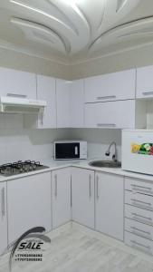 - une cuisine blanche avec des placards blancs et un évier dans l'établissement Элитная 2-комнатная квартира в районе Болашак, à Kooperator