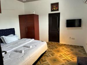 a bedroom with a bed and a flat screen tv at Nyawoyi villa in Tokuse