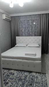 una camera con letto bianco e testiera bianca di Элитная 2-комнатная квартира в районе Болашак a Kooperator