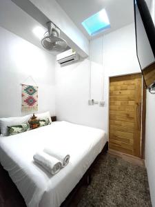 a bedroom with a white bed and a wooden door at Hanuman VIP Hostel - SHA Plus in Bang Tao Beach