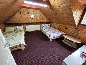 an attic room with two beds and a window at Cabana de lângă Vale in Budureasa