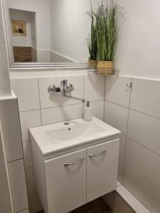 La salle de bains blanche est pourvue d'un lavabo et d'un miroir. dans l'établissement Pokoje goscinne Gala, à Międzyzdroje