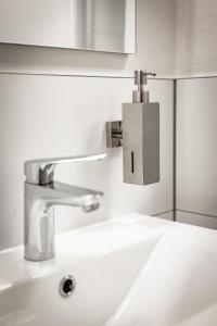 a bathroom sink with a silver faucet on the wall at Rennglück Apartments in Kelberg