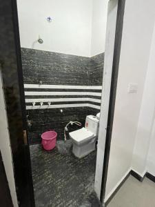 a bathroom with a toilet and a pink bucket at Rukmani Rooms in Mathura