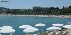 a beach with white umbrellas and a group of people at Camélias - Chambre privée, proche mer in Antibes