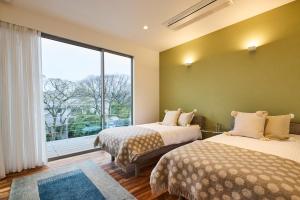 two beds in a room with a large window at i.1012 IZU in Ito +23 photos