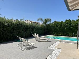 un patio avec deux chaises et une piscine dans l'établissement Villablanca, à Terrasini