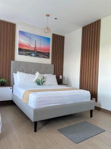 a bedroom with a large white bed with a painting on the wall at Cozy Belle Suite Relaxing Place at SMDC Hope Residences in Trece Martires