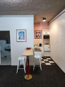uma cozinha com uma mesa de madeira e 2 bancos em West End Motel em Adelaide