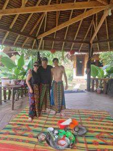 a group of three people standing on a colorful rug at Tangkahan Eco Glamping 