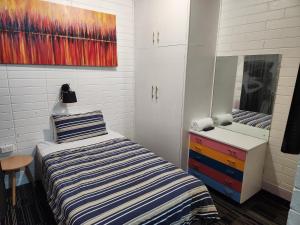 um quarto com uma cama, uma cómoda e um espelho em West End Motel em Adelaide