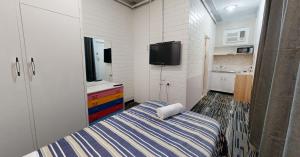 1 dormitorio pequeño con 1 cama y TV en West End Motel, en Adelaida