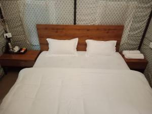a large white bed with two pillows and a telephone at YOLO RESORT in Dharān Bāzār