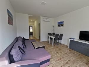 ein Wohnzimmer mit einem lila Sofa und einem Tisch in der Unterkunft Ferienanlage "Haus hinter den Dünen" Prerow in Prerow