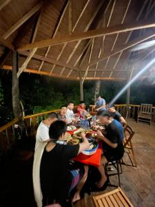 a group of people sitting at a table eating food at Tangkahan Eco Glamping 