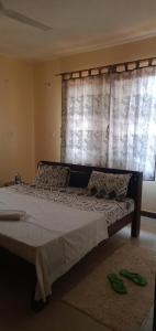 Cette chambre comprend un grand lit et une fenêtre. dans l'établissement Picho two bedroom apartment, à Malindi