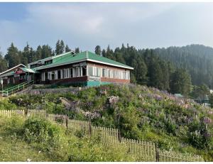 een huis op een heuvel met een bloemenveld bij Hotel Yemberzal & Restaurant, Jammu and Kashmir in Gulmarg