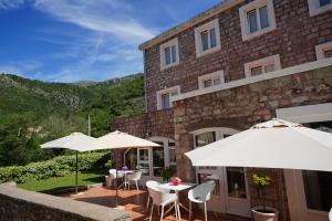 a patio with tables and umbrellas in front of a building at Apartments Pavlovic in Petrovac na Moru