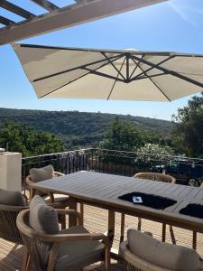 um pátio com uma mesa, cadeiras e um guarda-sol em Villa 10 P piscine lagon avec vue époustouflante proche Uzès em Saint-Maximin