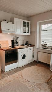 a kitchen with a stove and a washing machine at Lille hygge in Leck