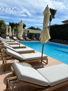 una fila di sedie a sdraio e ombrelloni accanto alla piscina di La Garoupe-Gardiole a Antibes