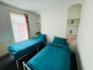 two beds in a room with a window at Entire 3 Bedroom House- FREE PARKING in Liverpool