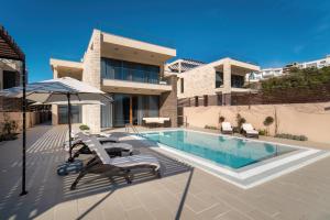 a swimming pool with chairs and an umbrella next to a house at Cape Montenegro Villas in Krimovice