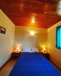 um quarto com uma cama azul com duas mesas de cabeceira em Les Loges de Mélis em Cuzorn
