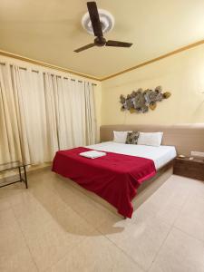 a bedroom with a bed with a red blanket and a ceiling fan at Shraddha hospitality in Calangute