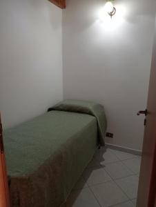 sypialnia z zielonym łóżkiem w białym pokoju w obiekcie Casa Anna w mieście Castellammare del Golfo