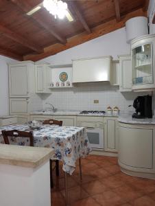 kuchnia z białymi szafkami i stołem z tkaniną w obiekcie Casa Anna w mieście Castellammare del Golfo