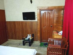 Habitación con cama y TV en la pared. en Karachi Motel Guest House en Karachi