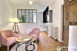 uma sala de estar com cadeiras cor-de-rosa e uma mesa em Les Chambres D'Hespéris em Pleyben