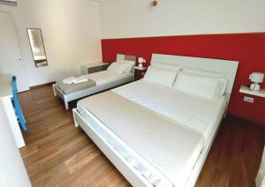 a bedroom with two beds and a red wall at Casa sulla Punta in Marina di Camerota