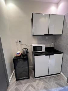 uma cozinha com armários brancos e um micro-ondas em أستديو تصميم أنيق هادي دخول ذاتي em Riyadh