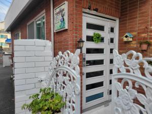 a white fence in front of a house with a door at Como Green House in Busan