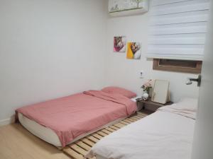 a bedroom with two beds and a window at Como Green House in Busan