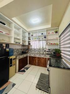 eine Küche mit Holzschränken und einem schwarzen Kühlschrank in der Unterkunft Elle's House in Dipolog City