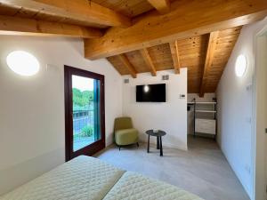 um quarto com uma cama, uma cadeira e uma televisão em Rio em Lignano Sabbiadoro