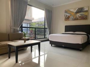 een slaapkamer met een bed, een bank en een tafel bij Hotel Bima Majalengka in Majalengka