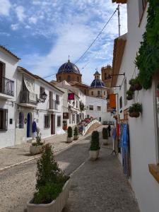 a street with white buildings and a church in the background at Bahia Vista - Chalet adosado con vista al mar in Finestrat