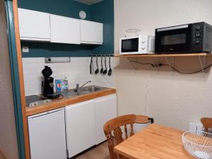 eine Küche mit weißen Schränken und einem Tisch mit einer Mikrowelle in der Unterkunft Joli studio à St Gervais les bains in Saint-Gervais-les-Bains