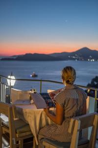 a woman sitting at a table reading a book at Hotel Adrović in Sveti Stefan