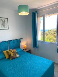 1 cama azul en un dormitorio con ventana en Residence Motel Corsicana, en LʼÎle-Rousse