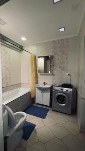 een badkamer met een toilet, een wastafel en een wasmachine bij ЖК «Caspyi Towers», 17-й микрорайон, 3 дом , 2 подъезд, 15 этаж , 114 кв. in Aqtau