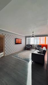 ein Wohnzimmer mit Sofas und einem TV an der Wand in der Unterkunft ЖК «Caspyi Towers», 17-й микрорайон, 3 дом , 2 подъезд, 15 этаж , 114 кв. in Aqtau